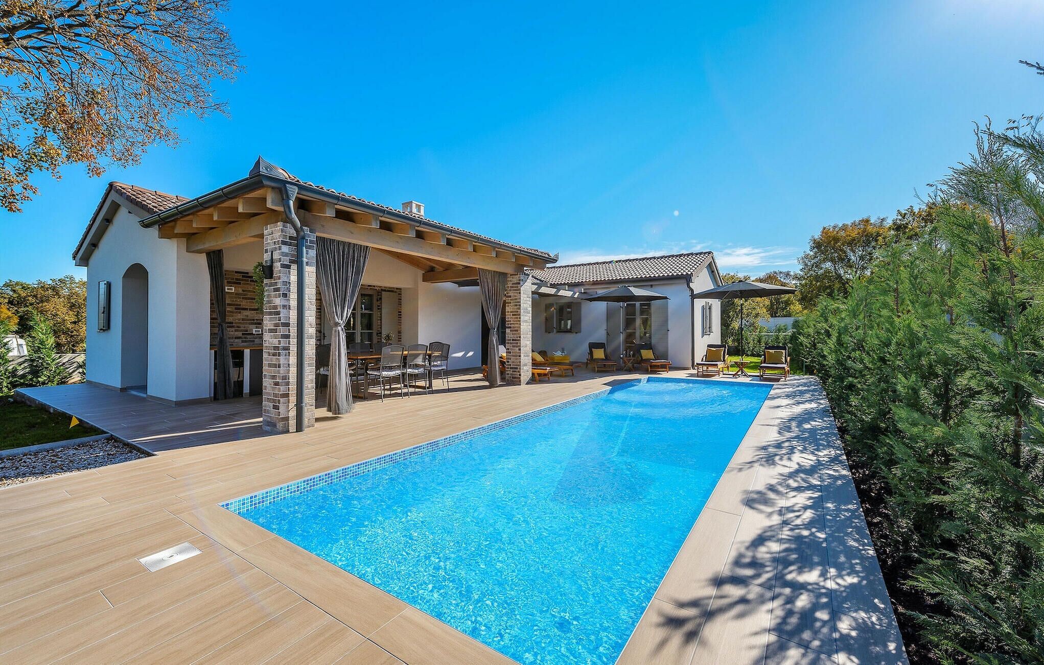 A modern house with a swimming pool, outdoor seating, and a pergola.