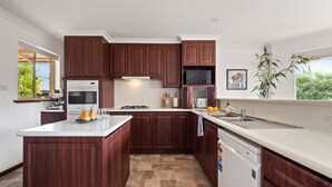 A modern kitchen with dark wood cabinets, a built-in oven, microwave, and dishwasher. - Whale Watch Family & Pet Friendly Augusta Retreat (Augusta)