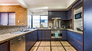 A modern kitchen with granite countertops, stainless steel appliances, and blue cabinetry. - Waterfront Bliss: Serenity & Adventure Await! (Geographe)