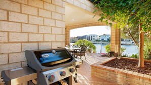 A barbecue grill with a view of a body of water and houses in the background. - Waterfront Bliss: Serenity & Adventure Await! (Geographe)