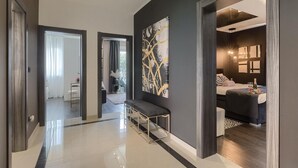 A modern hotel hallway with a bench, a large abstract painting, and a well-lit bedroom with a bed and bedside table. - Stunning home in Umag (Umag)