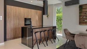 A modern kitchen with a central island, bar stools, and a dining area with a table and chairs. - Stunning home in Umag (Umag)