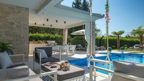 A poolside area with a covered seating area, outdoor furniture, and a pool. - Stunning home in Umag (Umag)