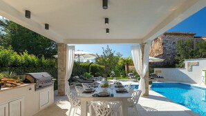 An outdoor dining area with a pool, white furniture, and a grill. - Stunning home in Umag (Umag)