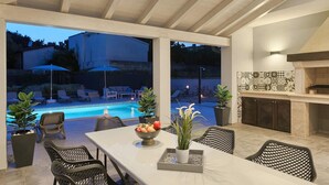 Un espace extérieur aménagé pour les repas, avec une piscine, des chaises longues et un barbecue.
