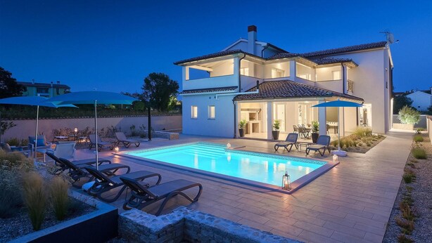 Une maison à deux étages dotée d’une piscine, d’un espace salon extérieur et d’un patio couvert.
