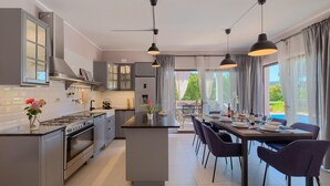 Uma cozinha moderna com ilha central, eletrodomésticos de aço inoxidável e iluminação pendente.