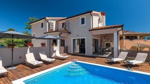 Uma casa de dois andares com piscina, área de estar externa e um pátio.