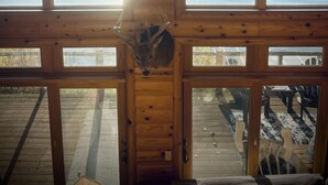 A cabin with a wooden interior, large windows overlooking a lake, and a view of a boat on the water. - Cozy Cabin on Lake Wisconsin
Skiing, Fishing & Hiking Retreat (Merrimac)