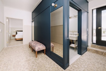 Spacious room with a large mirror, bench, and bathroom area. at Hotel Heron Old Town Alexandria