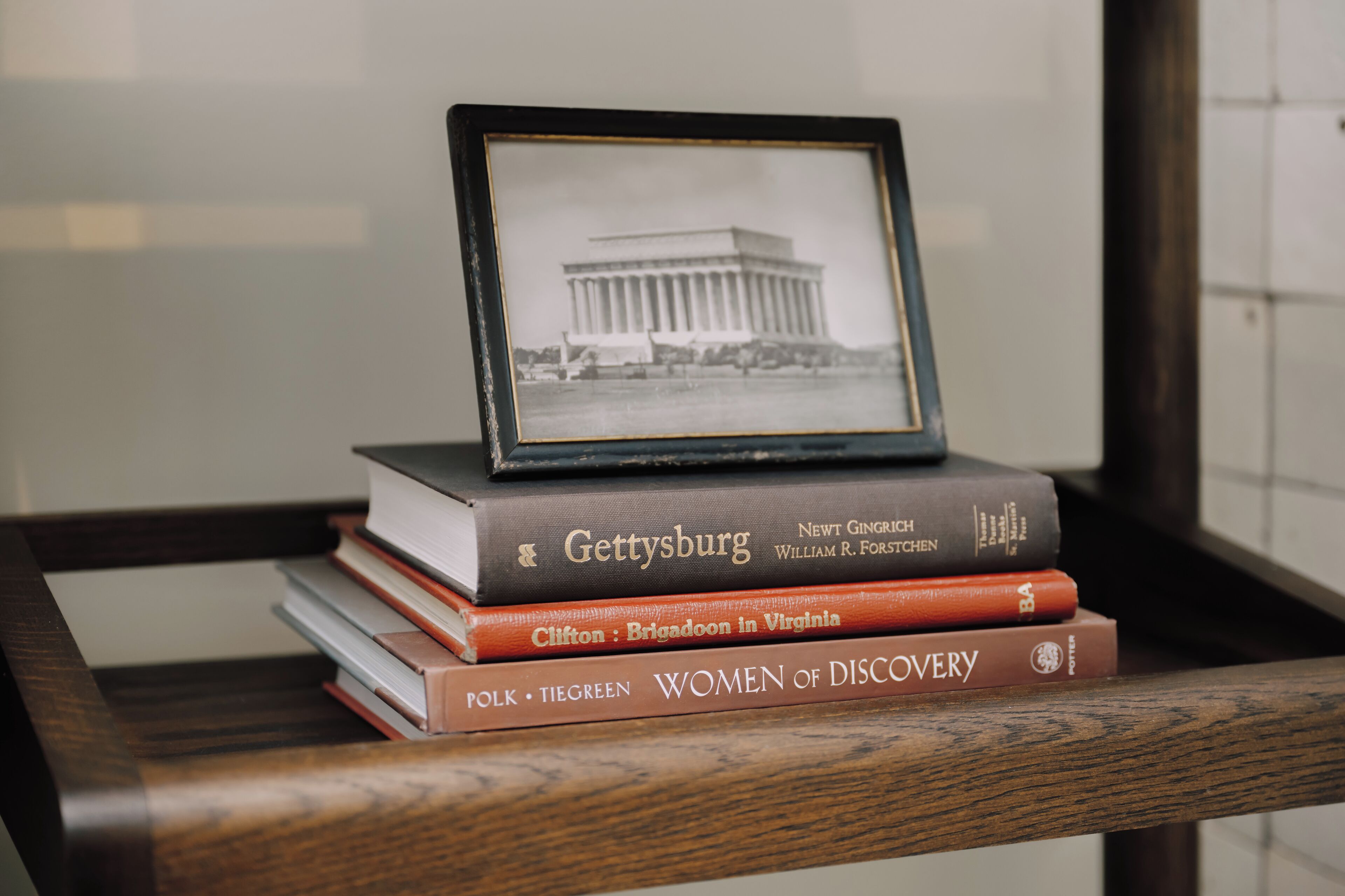 A stack of books with a framed photo of a building on top.