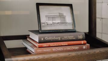 A stack of books with a framed photo of a building on top.