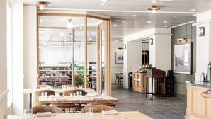 Un restaurante moderno con mesas y sillas de madera, una zona de bar y vistas a la cocina.