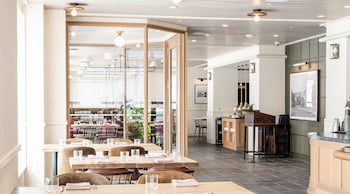 Enjoy meals and drinks in a spacious dining area with a clear view of the kitchen, a bar, and comfortable seating for several guests. at Hotel Heron Old Town Alexandria