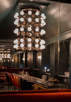 Enjoy a sophisticated dining experience in this stylish space, featuring a unique chandelier, polished bar, and plush seating. at Hotel Heron Old Town Alexandria
