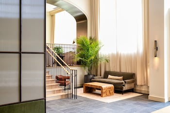 Relax in a spacious living area with a sofa, coffee table, and potted plant, and access to a staircase leading to an upper level. at Hotel Heron Old Town Alexandria