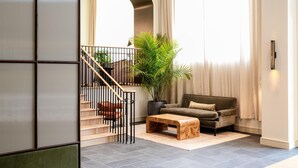 Una sala de estar moderna con una escalera, un sofá, una mesa de centro y una planta grande en maceta.