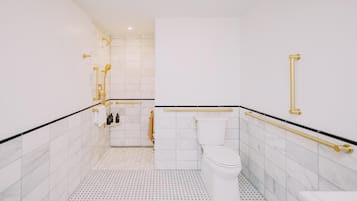 Un baño moderno con azulejos blancos, un inodoro blanco y detalles dorados.