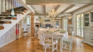 A spacious dining area with a high ceiling, exposed beams, and a chandelier. A brick column and stone wall add rustic charm. - Pet friendly home in Tinjan (Tinjan)