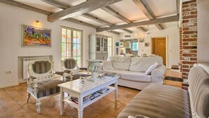 A spacious living room with exposed wooden beams, a fireplace, a white sofa, and a dining area. - Pet friendly home in Tinjan (Tinjan)