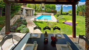An outdoor dining area with a pool view, stone pathway, and a stone building in the background. - Pet friendly home in Tinjan (Tinjan)