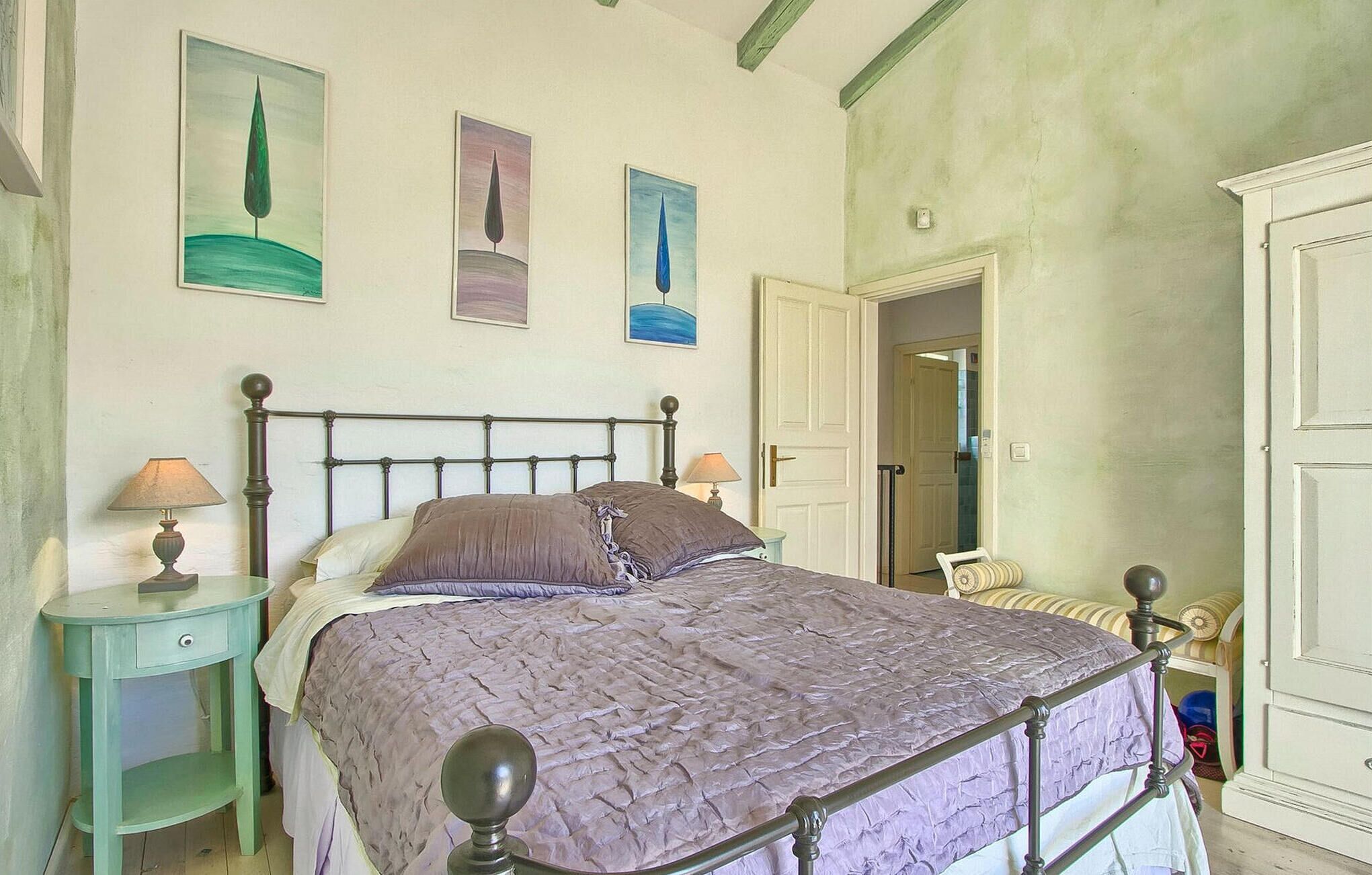 Ein Schlafzimmer mit einem Bett, zwei Nachttischen und drei an der Wand befestigten Bildern.