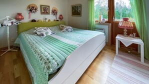 Un dormitorio con cama, mesita de noche, lámpara y ventana con cortinas.