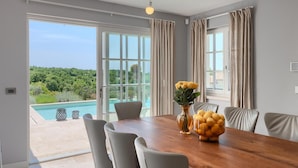 Un coin repas avec une table en bois, des chaises et un vase rempli de fleurs jaunes.
