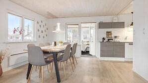 A modern kitchen with grey cabinets, a dining area with a wooden table and grey chairs, and a view of the outside through large windows. - Amazing home in Haderslev with WiFi (Haderslev)