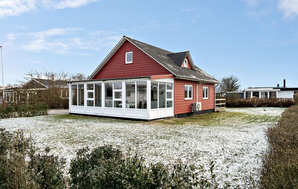 A red house with a large glass bay window, surrounded by a grassy area with some snow. - Amazing home in Haderslev with WiFi (Haderslev)