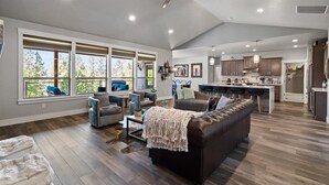 A spacious living area with a large sofa, multiple seating options, and a kitchen in the background.