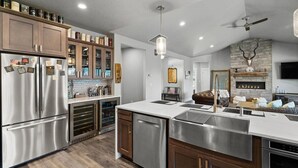 A modern kitchen with stainless steel appliances, wooden cabinets, and a stone fireplace.