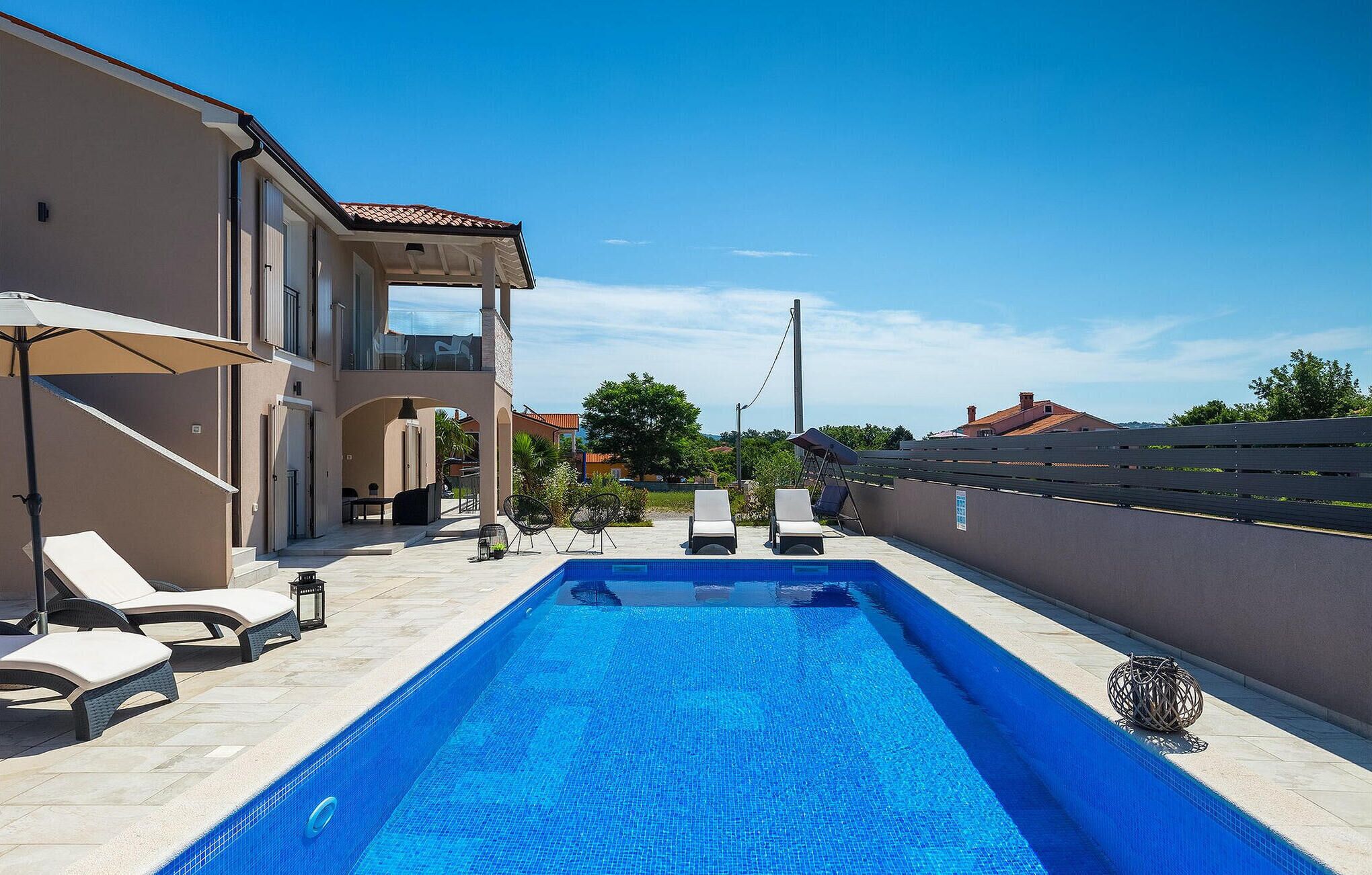 A swimming pool with lounge chairs and a covered patio area.