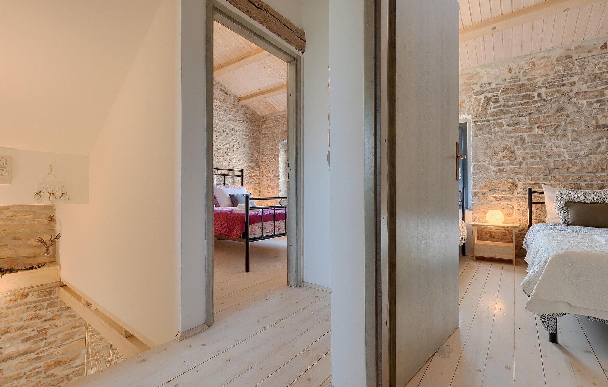 Ein Schlafzimmer mit einer Steinwand, einem Bett mit weißer Bettdecke und Holzboden.
