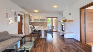 A modern living room with a glass coffee table, a sofa, and a kitchen area with a dining table and chairs. - Beautiful home in Marcana (Marcana)