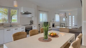 A modern kitchen with white cabinets, a dining table with chairs, and a fireplace. - Stunning home in Sveti Petar u Sumi (Sveti Petar u Sumi)
