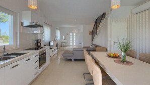 A modern kitchen with a central island, a dining area with a sofa, and a staircase leading to another level. - Stunning home in Sveti Petar u Sumi (Sveti Petar u Sumi)