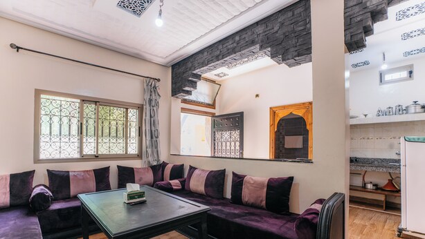 A living room with a sofa set, a coffee table, and a kitchen area with cabinets and a refrigerator. - The Best Apartments of Ourika Valley (Vallée de l'Ourika)