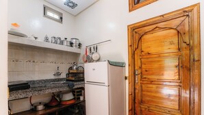 A compact kitchen with a white refrigerator, wooden cabinets, and a wooden door. - The Best Apartments of Ourika Valley (Vallée de l'Ourika)