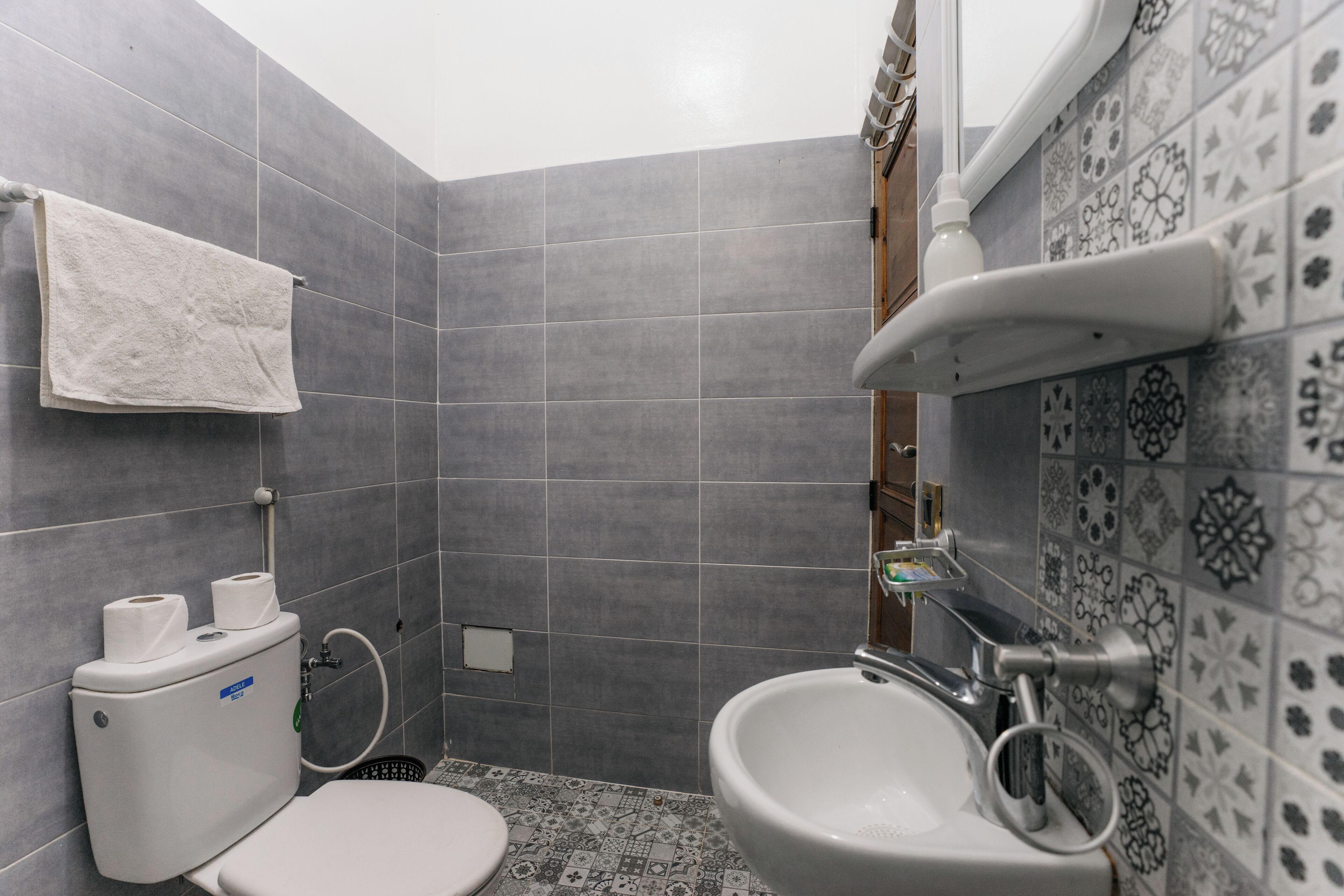 Ein Badezimmer mit grauen Fliesen, einer Toilette, einem Bidet und einem Waschbecken.