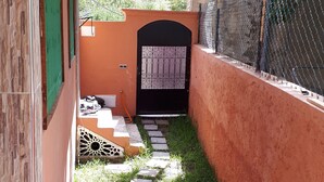 A narrow pathway leading to a gated entrance with a decorative door, surrounded by a low wall and a fence. - The Best Apartments of Ourika Valley (Vallée de l'Ourika)