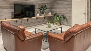 Un saló modern amb sofàs de cuir, una taula de centre, televisió de pantalla plana i plantes en testos.