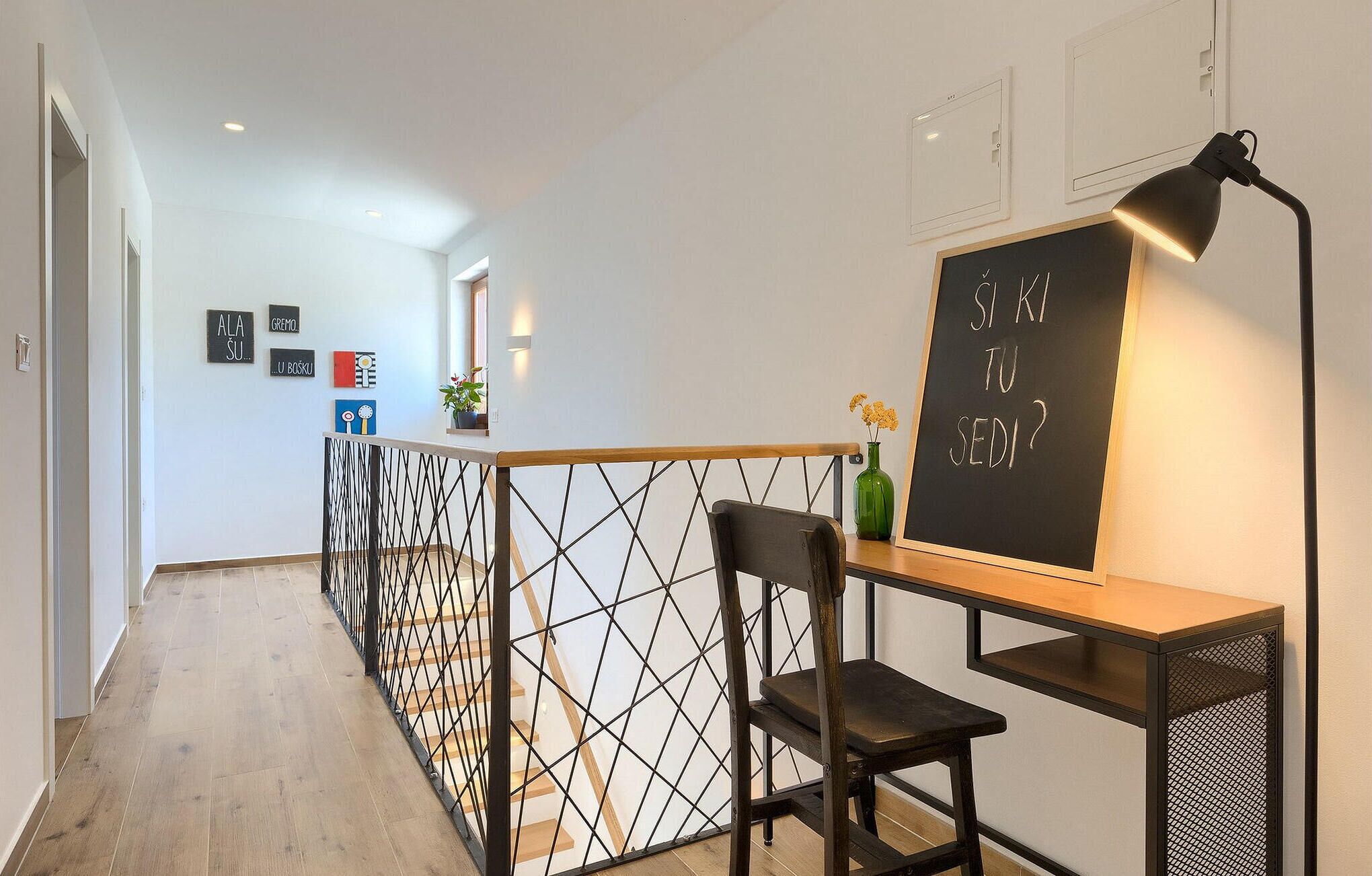 Un intérieur moderne avec un bureau, une chaise et un tableau noir sur lequel est écrit du texte.