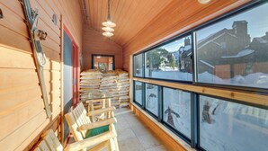 A wooden interior with a large window, wooden benches, and a stack of bags against the wall. - Mammoth Lakes Condo - Steps to Ski Lift! (Mammoth Lakes)