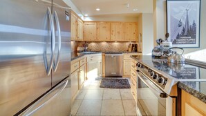 A modern kitchen with stainless steel appliances, wooden cabinets, and a granite countertop. - Mammoth Lakes Condo - Steps to Ski Lift! (Mammoth Lakes)
