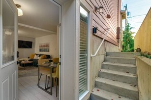 Un interior moderno con comedor, escalera y sala de estar con sofá y un cuadro.