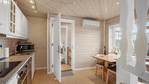 Une cuisine moderne avec des meubles en bois, un four à micro-ondes encastré et un coin repas comprenant une table et des chaises.