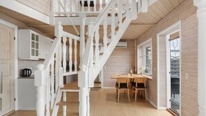 Un intérieur en bois comprenant un escalier, un coin repas et une cuisine.