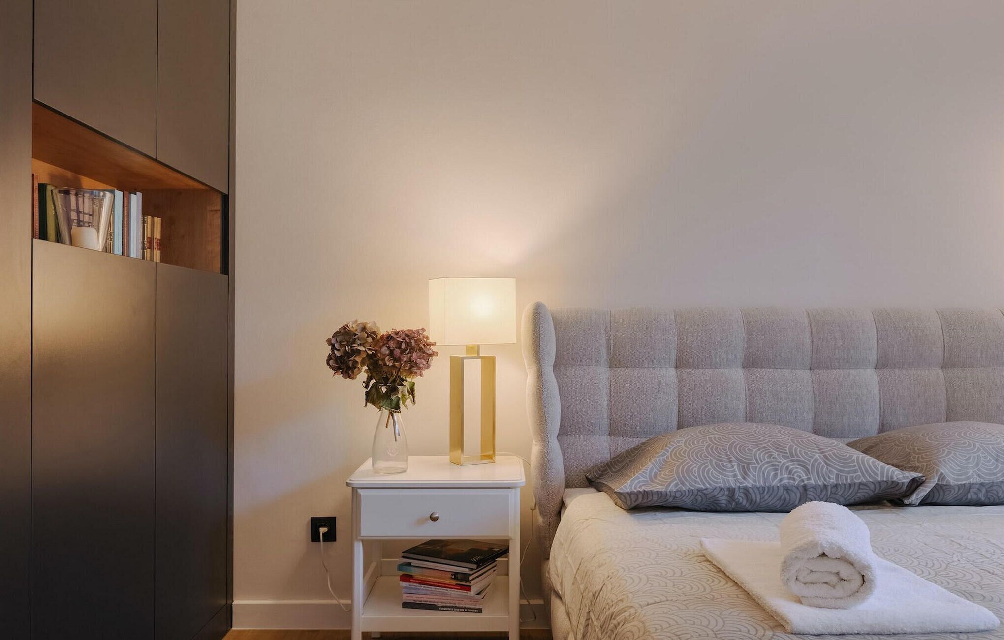 Une chambre bien rangée, avec un lit, une table de chevet et une bibliothèque.