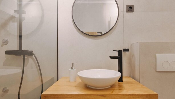 Une salle de bain avec un meuble-lavabo en bois, un lavabo blanc, un miroir et une douche.